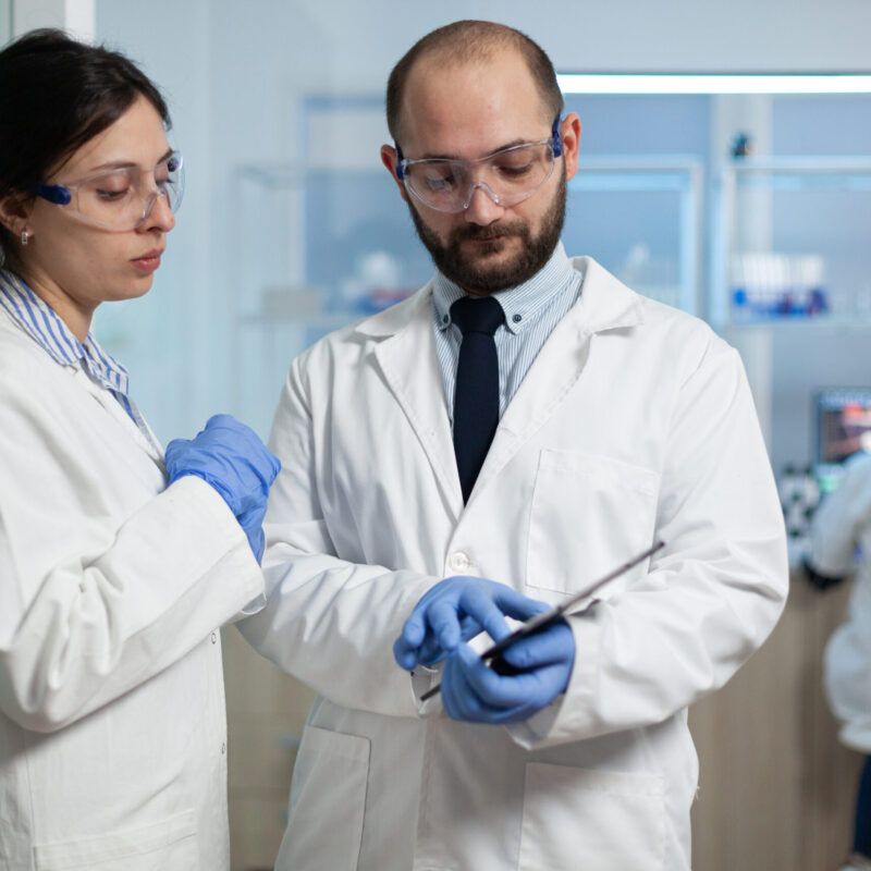 Scientist woman analyzing virus expertise with biologist researcher dicussing prevention treatment during clinical examination in microbiology hospital laboratory. Sickness investigation